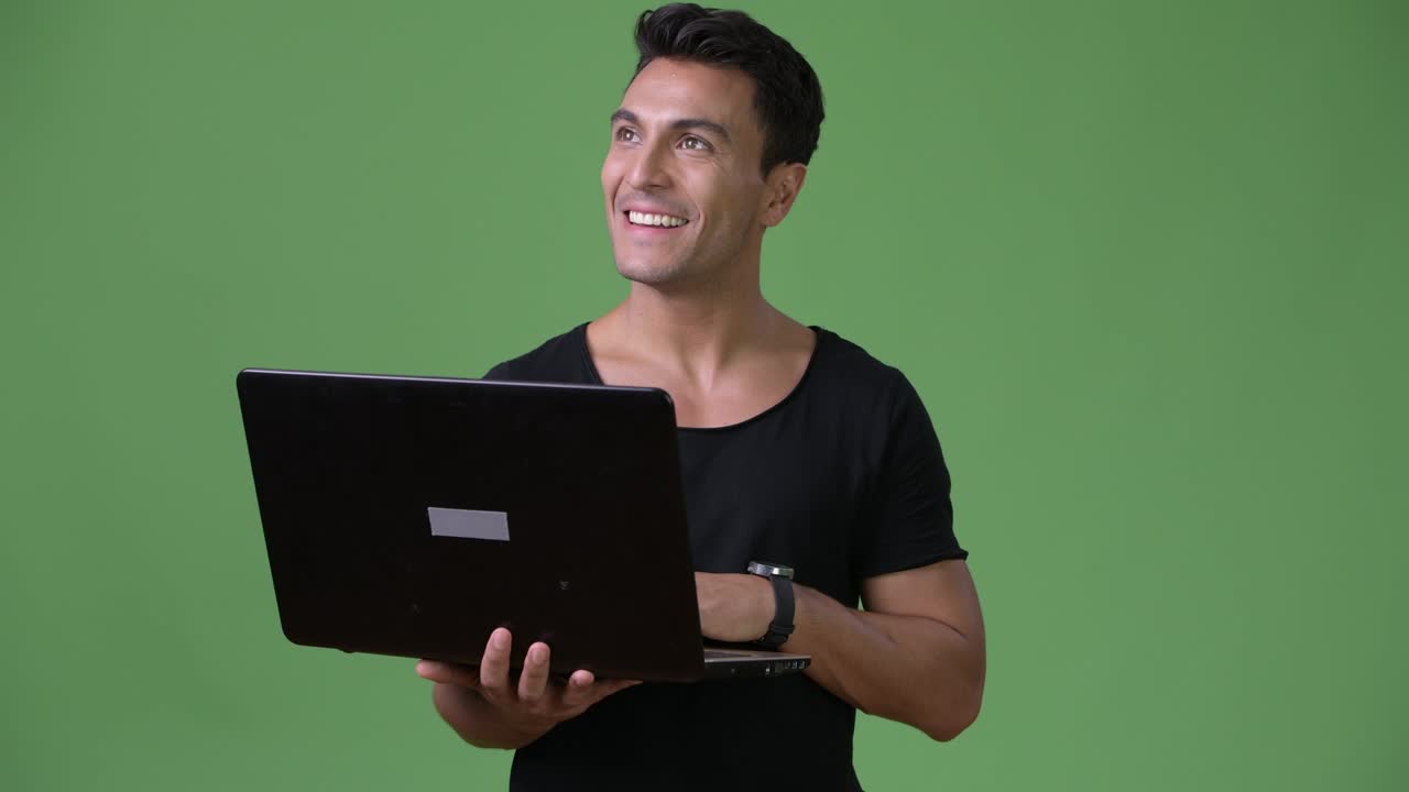 joven y guapo hombre hispano contra un fondo verde