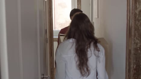 young couple holding big cardboard box together and carrying it through the corridor