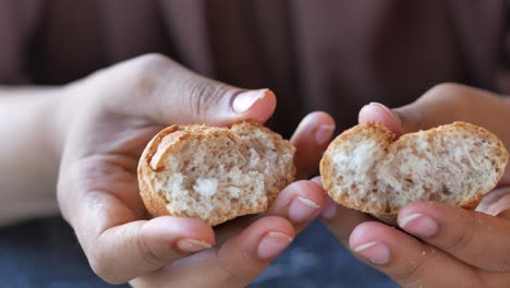 hands holding and breaking a piece of bread