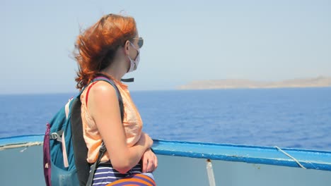 girl with red hair traveling on the gozo channel line ferry from malta to gozo island, looking towards the front of the boat over the ocean