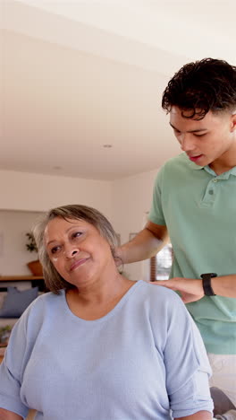 vertical video: giving neck massage, male physiotherapist treating senior female patient at home
