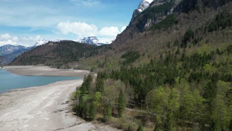 aerial forward view of shoreline of an alpine lake in a fantastic mountain landscape