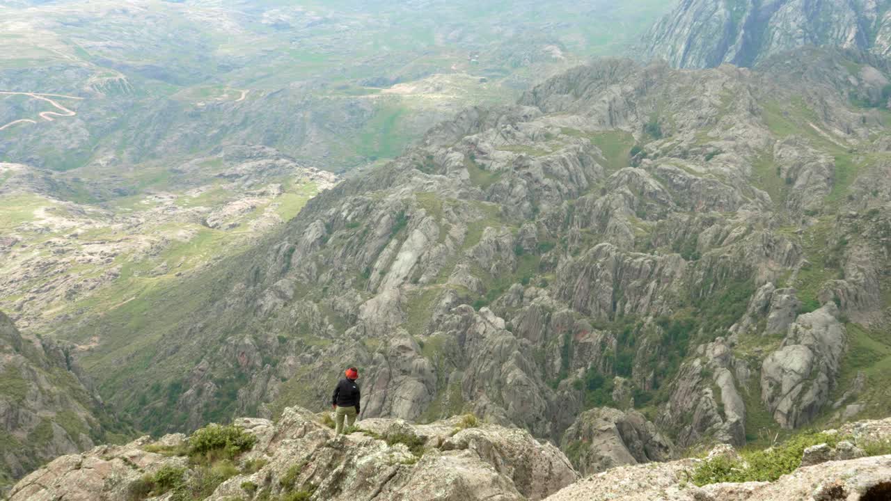 exitosa joven excursionista en la cima de la montaña cerca del borde de un acantilado