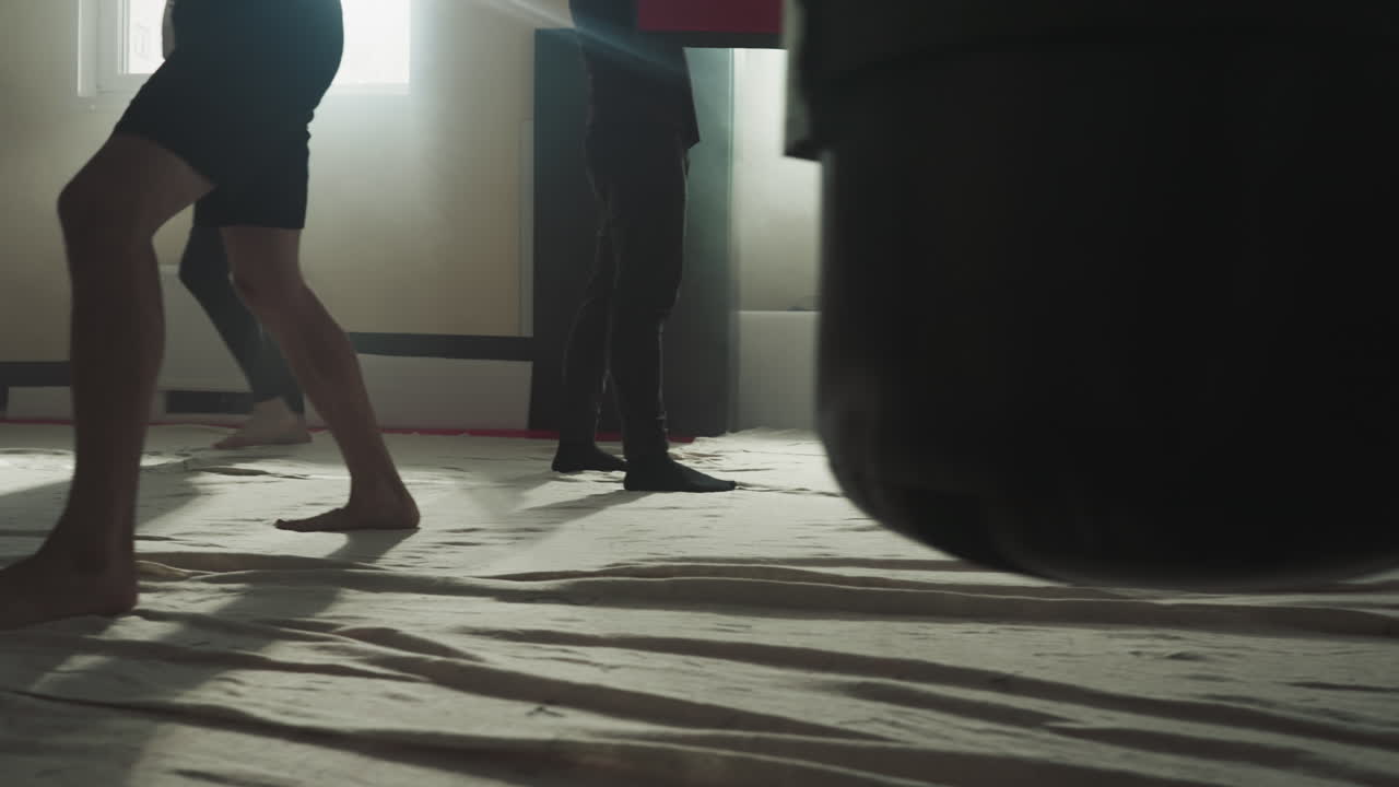 Fighters train kicking punching bags in sports club closeup. Skilled kick-boxers group exercises with heavy items in fighting gym slow motion