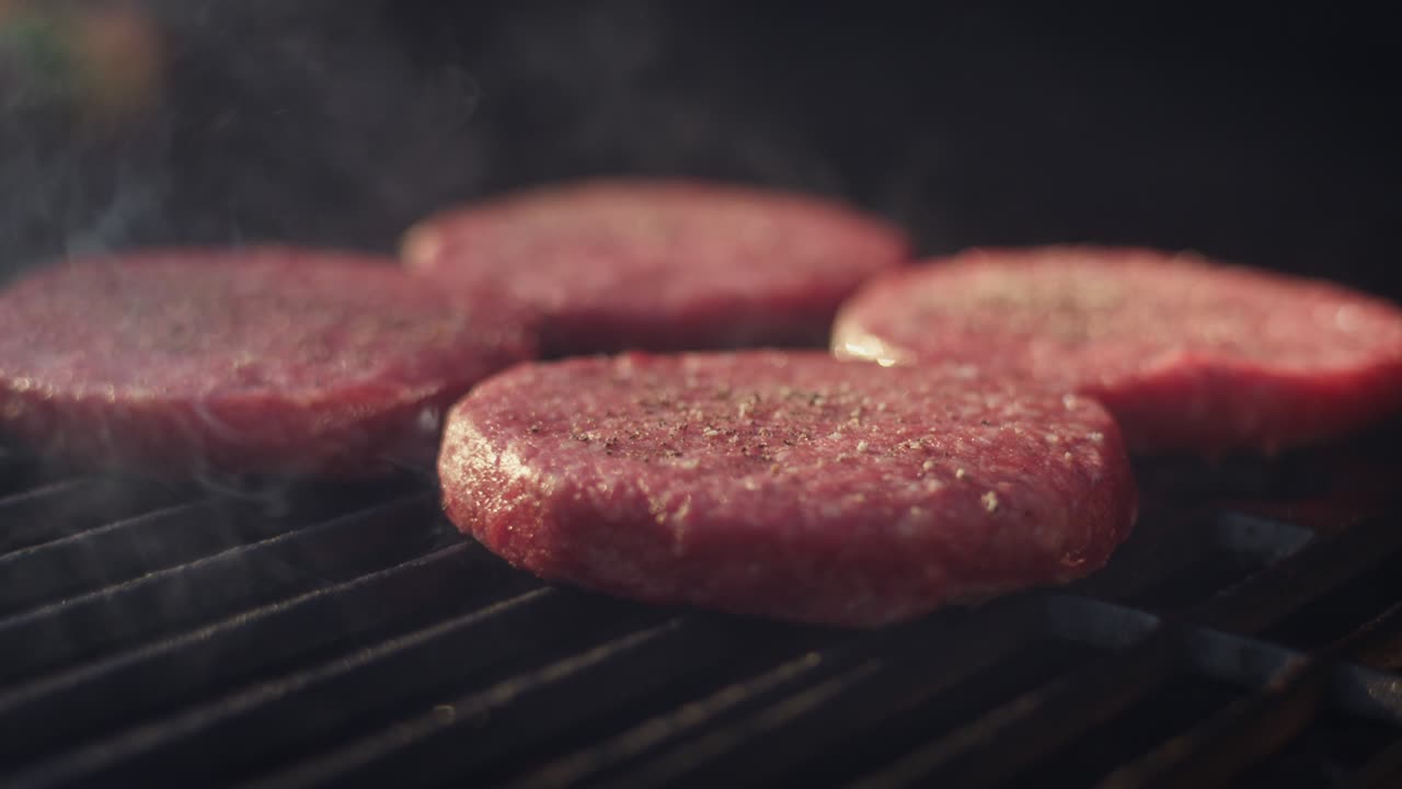 las sabrosas hamburguesas se enfocan con el humo que se eleva por todas partes