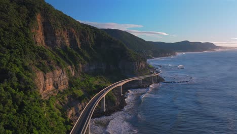 sunrise sea cliff bridge costal drone view iconic famous stanwell park waves ocean crashing south coast nsw australia landscape royal national park wollongong coalcliff iiawarra sydney forward pan up