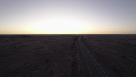 Una-Carretera-Desierta-Vacía-Al-Atardecer,-Disparo-De-Drones