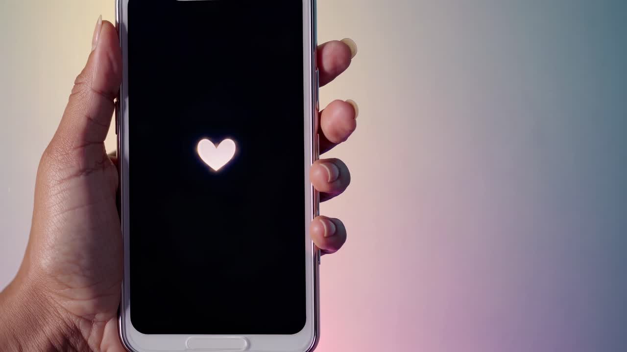 Mano che tiene uno smartphone con icone a cuore sullo schermo