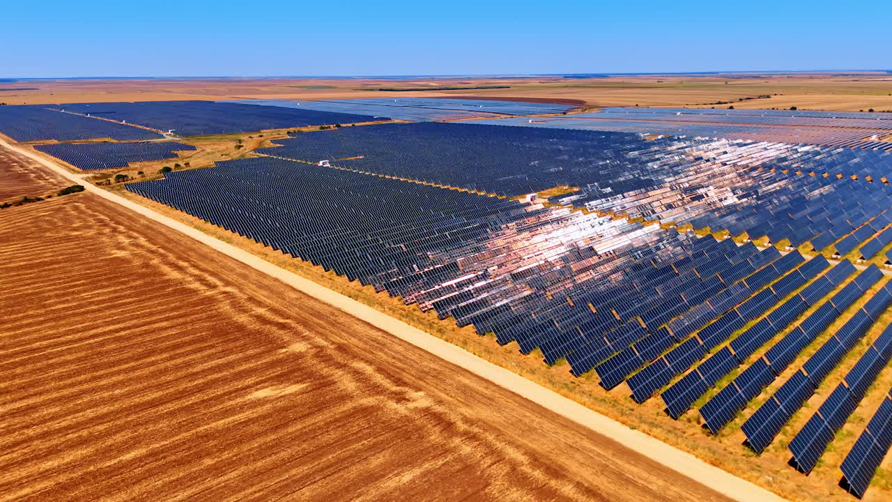 Expansive solar farm under clear sky. Vast solar panels stretch across fields, basking in sunlight on a clear day, highlighting renewable energy efforts