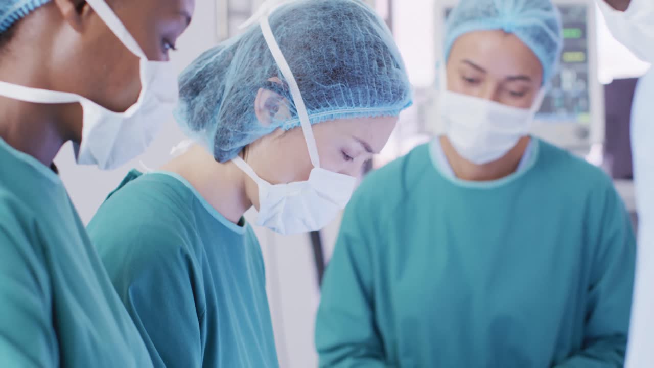 아시아 여성 외과 의사가 다양한 동료들과 함께 수술실에서 카메라를 바라보는 비디오