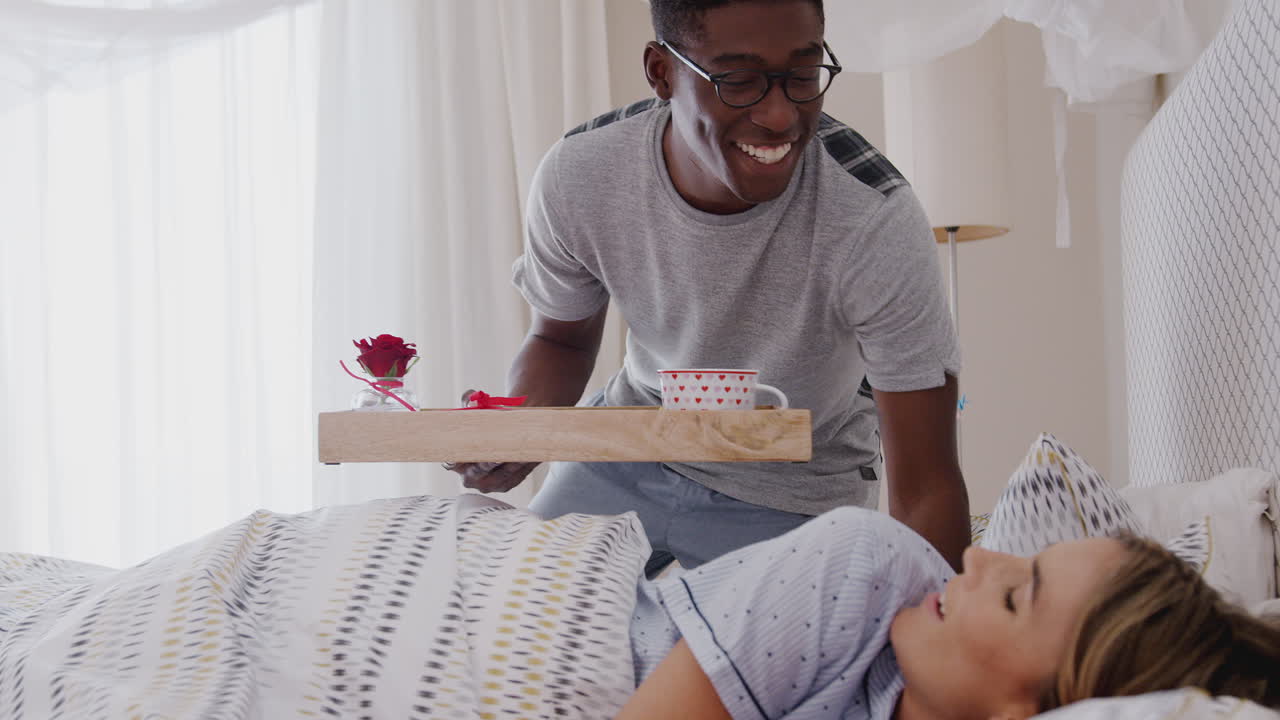 Uomo che porta la colazione a letto alla donna per festeggiare il compleanno o San Valentino.