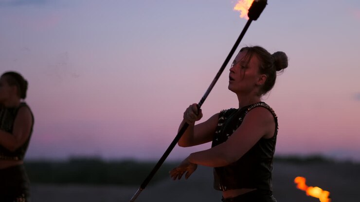 Un gruppo di artisti circensi professionisti con spettacoli di fuoco e danza al rallentatore, che usano lanciafiamme e ruotano torce con oggetti in fiamme