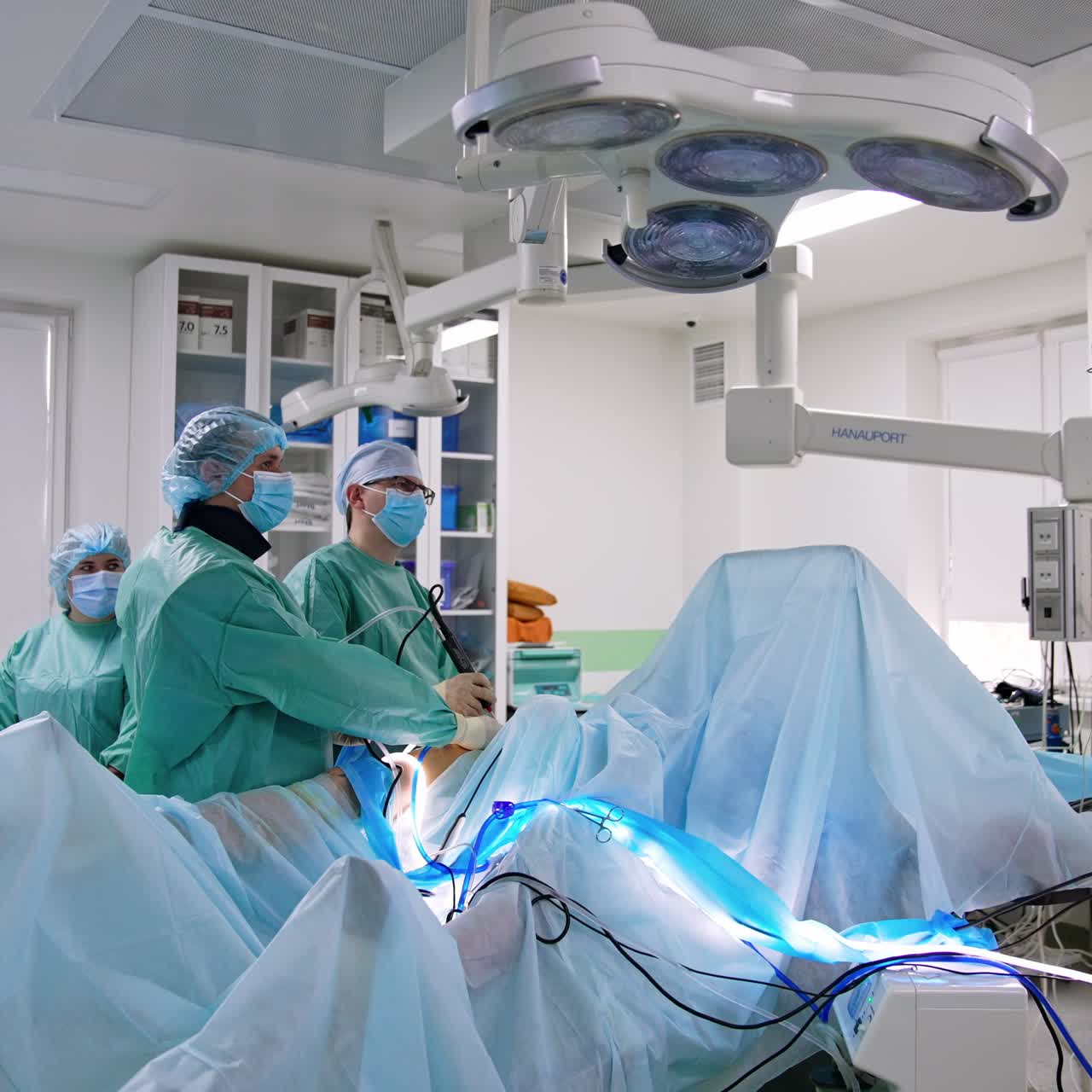 Thigh surgery in modern hospital. Professional use laparoscopic device operating the patient. Doctors look at the monitor during surgery