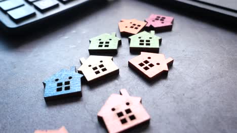 colorful wooden house miniatures on a desk with calculator and keyboard