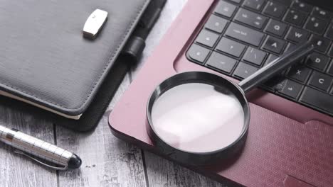 laptop with magnifying glass and notebook