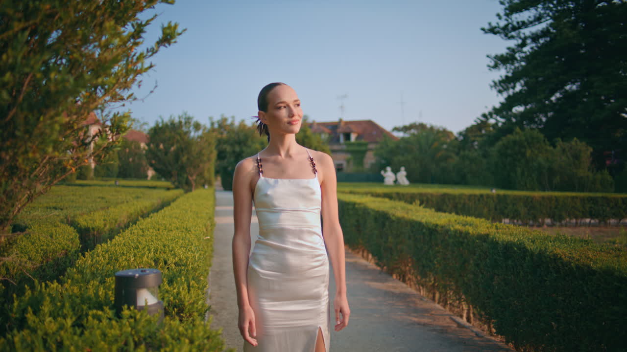 정원 길 에서 덤불 을 산책 하는 무관심 한 여자. 공원 초록색 을 즐기는 소녀