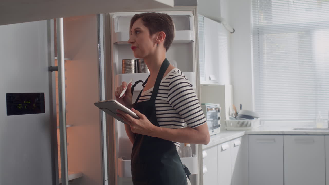 Housewife Checking List of Products when Cooking at Kitchen