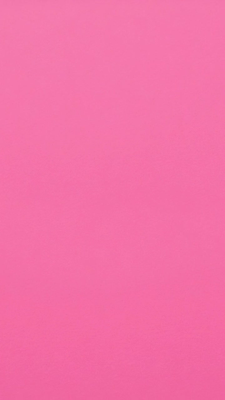 Vertical video: Showing stationary camera filming uniform pink surface in close-up, plain backdrop