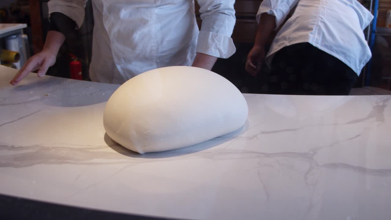 Lo chef impasta l'impasto della pizza sul tavolo della cucina in un ristorante.