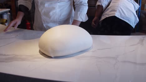 chef amasa la masa de pizza en la mesa de la cocina en un restaurante