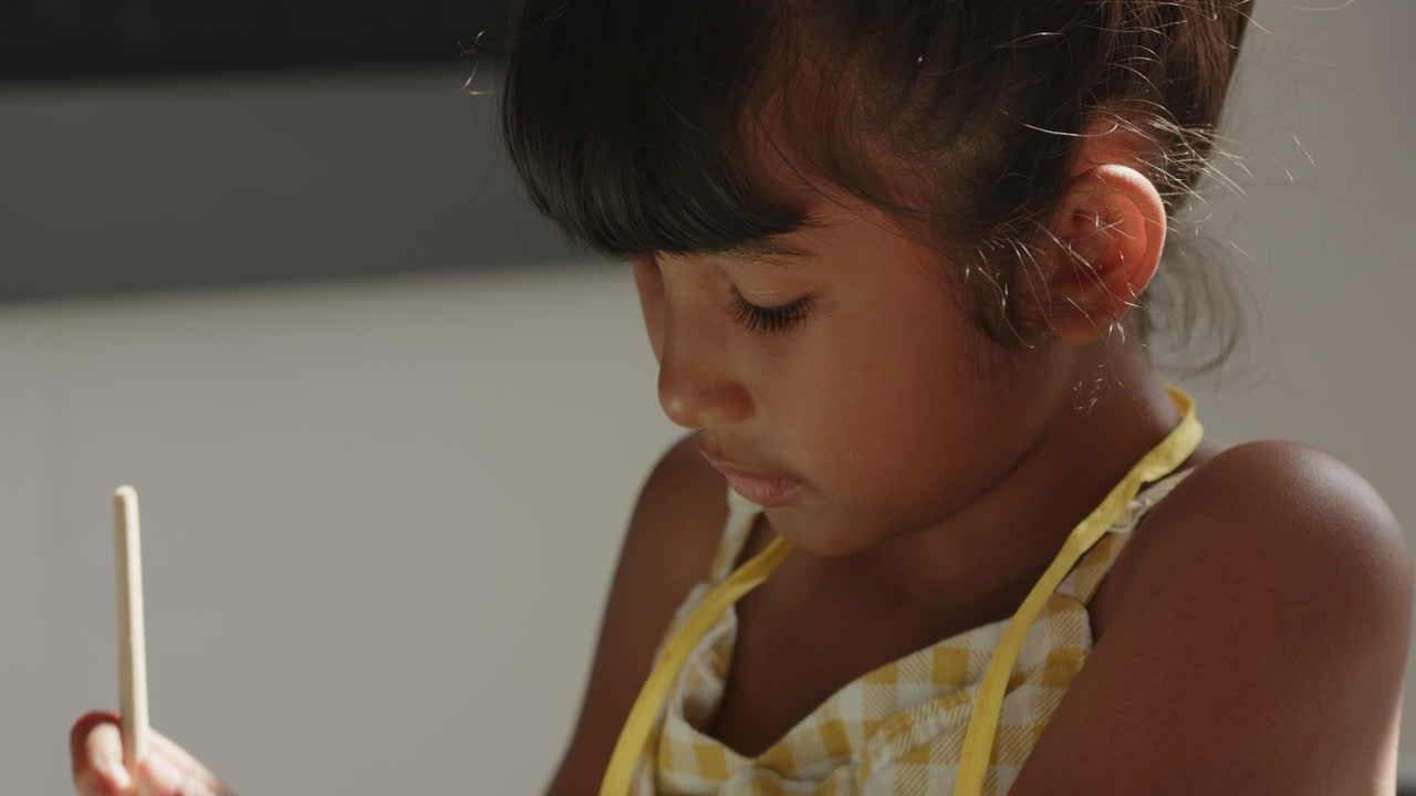 In school, child focusing on task, holding pencil and writing in classroom