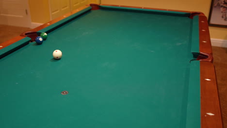 man wins a game of pool by shooting a bank shot on the eight ball into the side pocket of a brunswick table with green felt in the basement of a home, billiard games