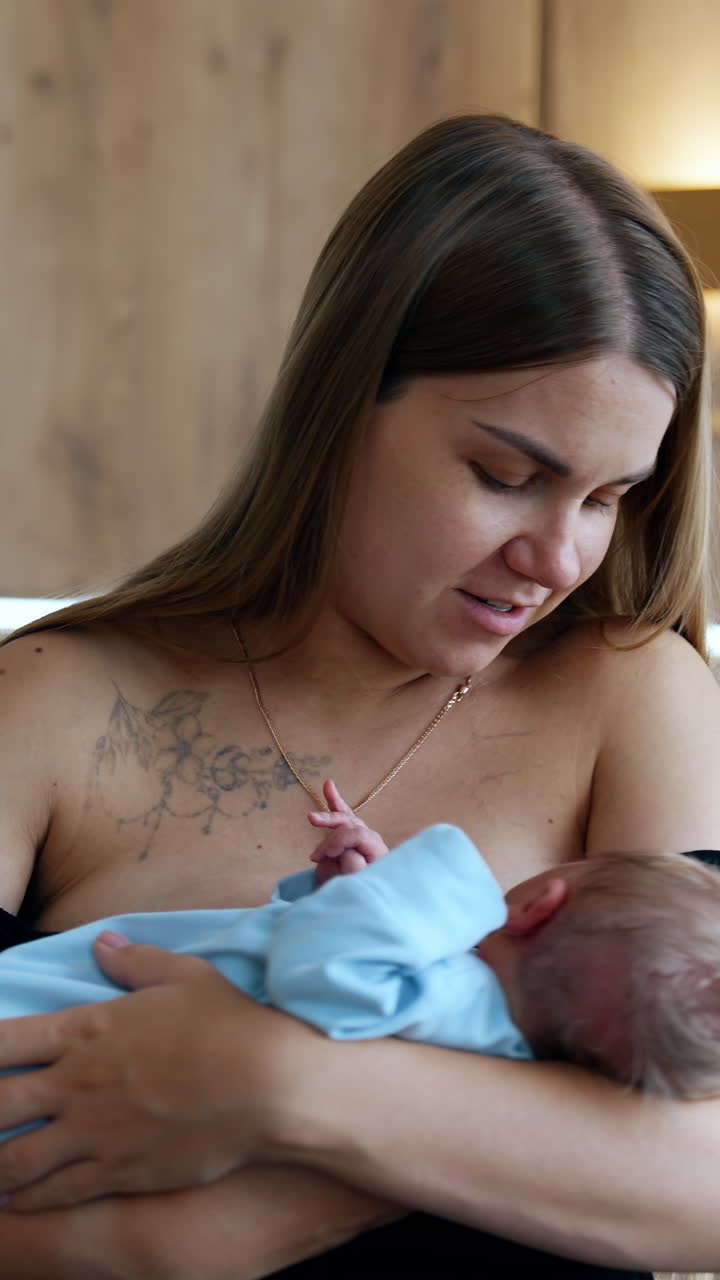 Long-haired Caucasian mother waving a newborn in hands. Happy woman canoodling her baby. Vertical video