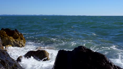 Meereswellen,-Die-An-Einem-Windigen-Sommertag-Mit-Strahlend-Blauem-Himmel-Im-Mittelmeer-Auf-Klippen-Und-Kamera-Spritzen