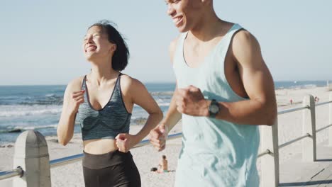 happy biracial couple running on promenade, in slow motion