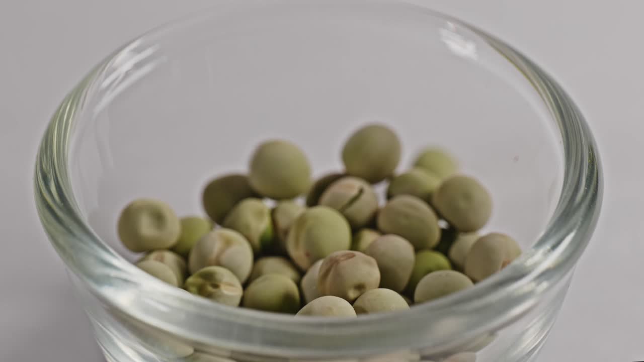 dried green peas falling in small glass bowl, 4k, stable shot