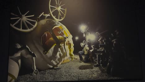 banksy art showing a pumpkin coach from disney crashed and a lot of reporters and paparazzi people around it filming and photographing it with flashing lights during night time. princess is harmed.