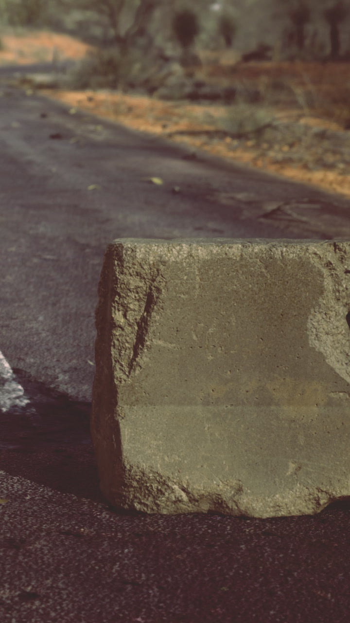 Cracked concrete block on a road during afternoon light in a rural area