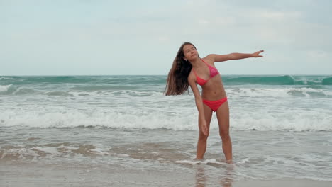 Young-woman-standing-at-seaside.-Beautiful-girl-doing-exercises-at-coastline.