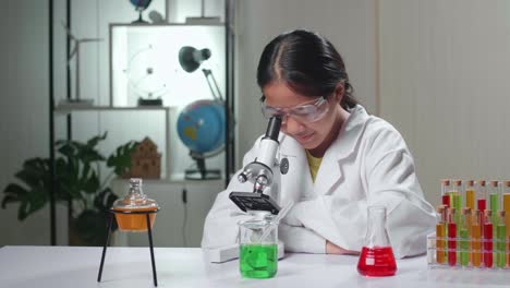 excited young asian scientist girl looking at microscope and say wow