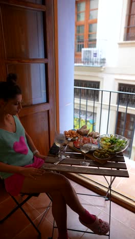 woman enjoying a meal on a balcony with a city view