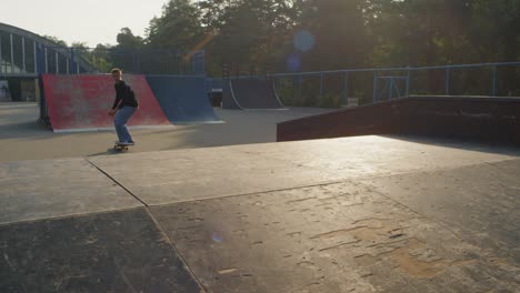 young man in sweatshirt and jeans practicing skateboarding in skate park 1