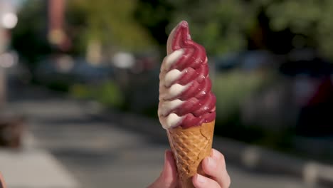 Mano-Sosteniendo-Un-Cono-De-Helado-Suave-Y-Colorido-Y-Girándolo-Sobre-Sí-Mismo-En-Un-Agradable-Día-De-Verano