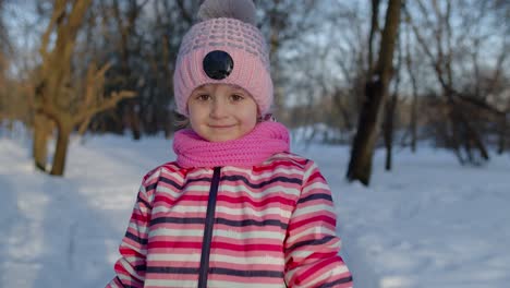 Smiling-child-kid-walking,-having-fun,-relaxing,-looking-around-on-snowy-road-in-winter-park-forest