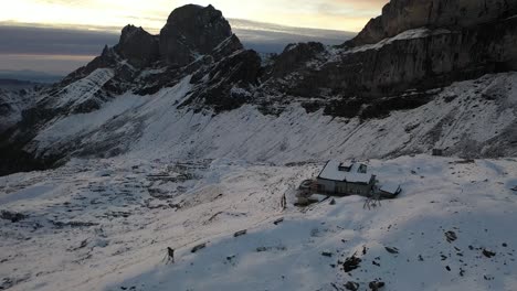 Disparo-De-Drones-Moviéndose-Hacia-Atrás-Filmando-La-Cabaña-De-Montaña-De-Rugghubelhutte-Y-La-Casa-En-La-Cima-De-La-Montaña-Nevada