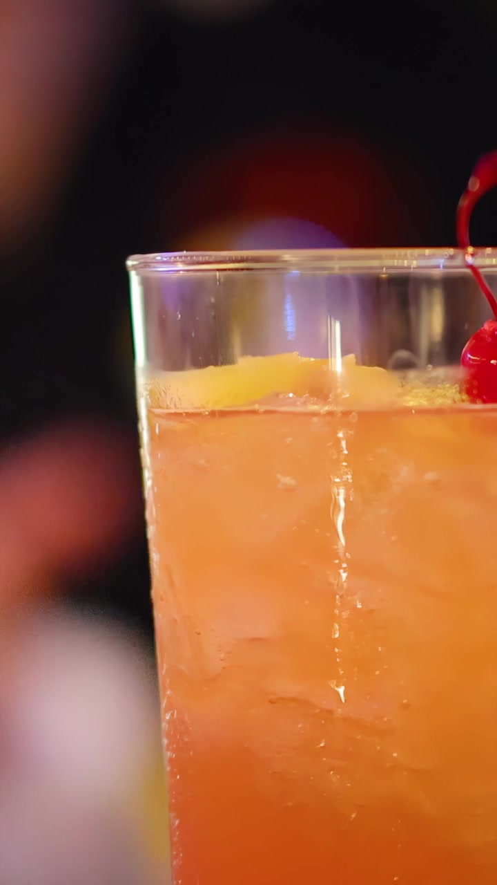 Un cocktail alto ghiacciato cambia colore mentre il barista lo mescola, illuminazione vibrante da discoteca, prospettiva ravvicinata.