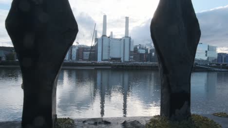 pull back shot of battersea power station under repairs revealing thames path fence