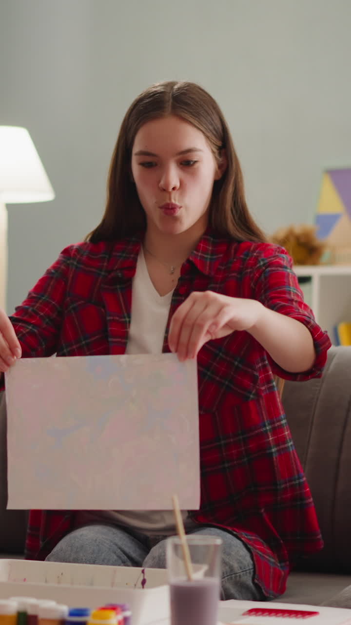 hermanos y hermanas miran una imagen emocional en papel en estilo de diseño erbu hecha juntos en casa en cámara lenta. técnica de diseño turco para la familia diversión ocio