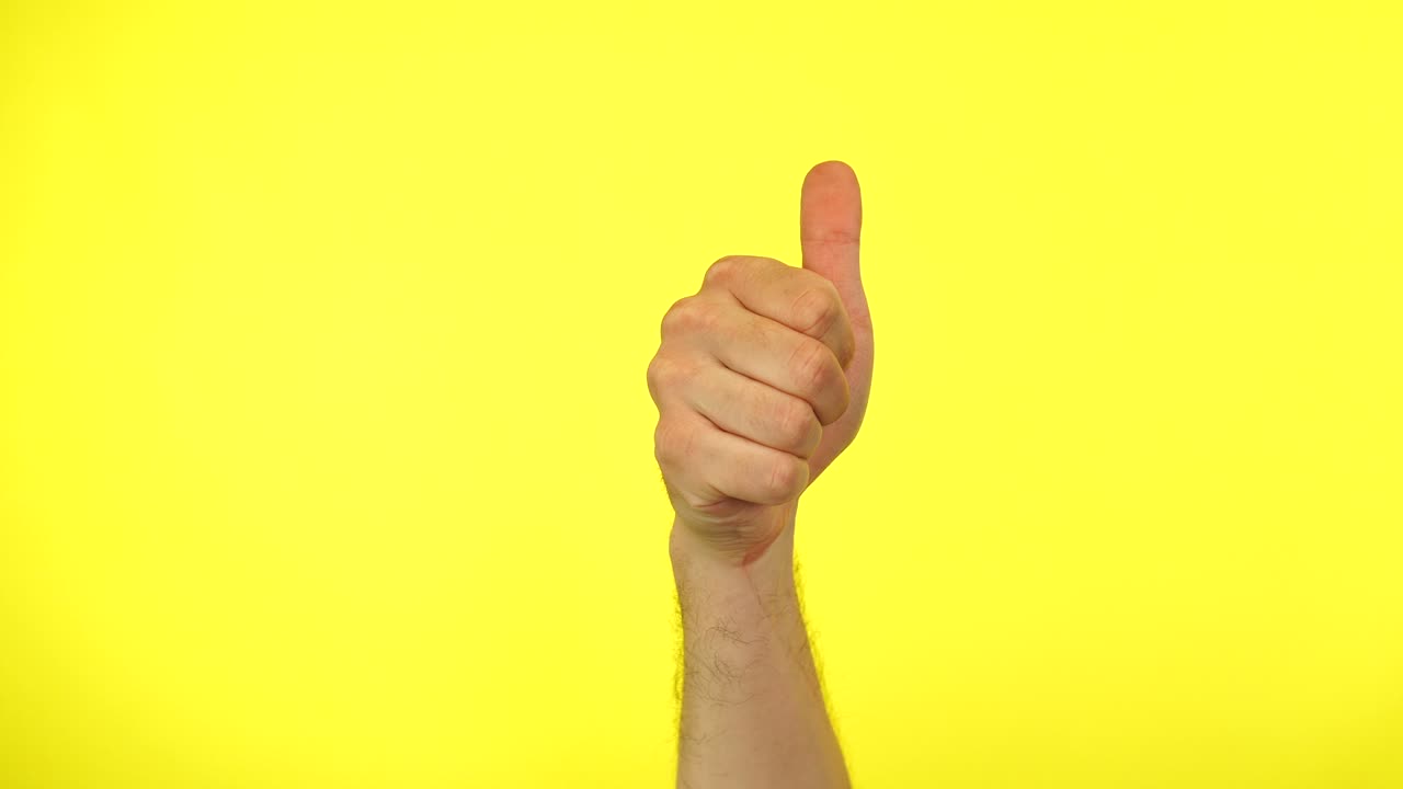 la mano del hombre gestando los pulgares hacia arriba, como o símbolo de signo positivo. fondo amarillo