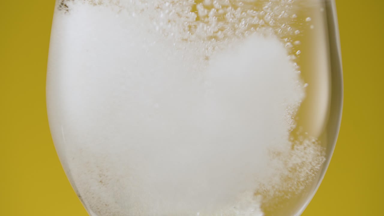 Closeup slow motion dropping a fizzy aspirin vitamin tablet in fresh clear water