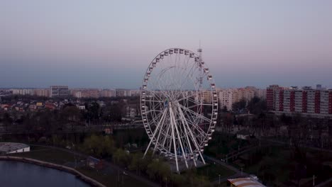 aerial view of spinning ferris wheel at sunset in the crowded city