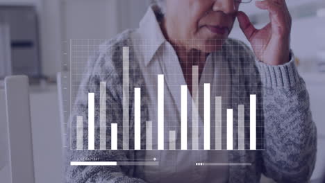 animación de datos financieros sobre una mujer biracial mayor usando una computadora portátil