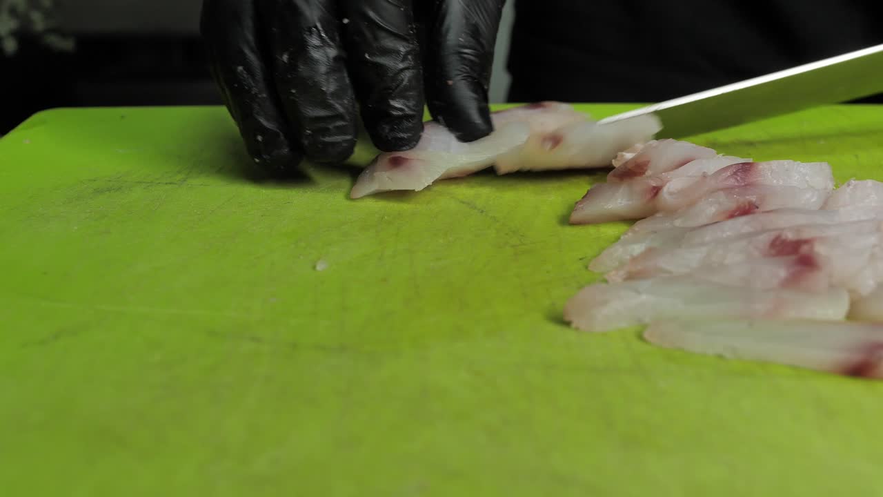 인식할 수 없는 요리사가 녹색 커팅 보드에 신선한 생선 고기를 자르고 닫습니다.
