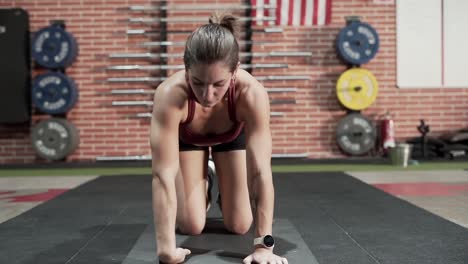 woman doing a kneeling plank exercise in a gym.