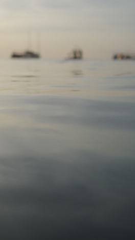 calm water surface with boats in the distance