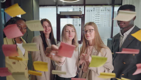 retrato de un equipo multiétnico de trabajadores de oficina a través de una pared de vidrio con notas post-it en la oficina